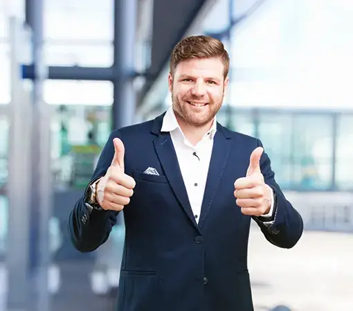 A young man in a suit showing 2 thumbs up and a smiling happy expression