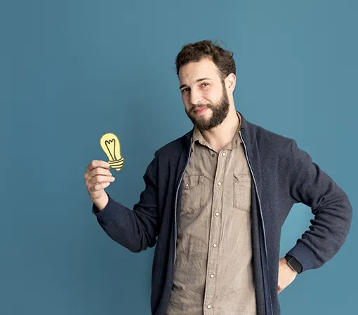 Bearded man holding a paper light bulb indicting creative ideas