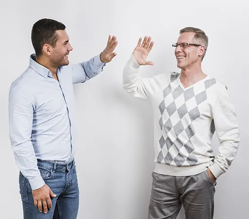 A young man and a middle-aged man giving high five indicating trustworthiness and good relationship