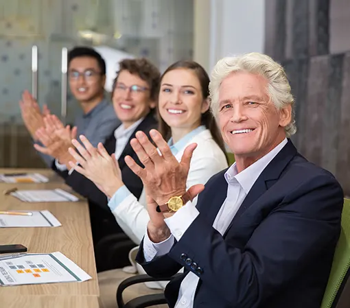 Business clients sitting at a desk clapping and smiling because of flawless results