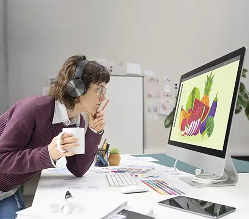 Experienced graphic designer editing a photo on her computer listening to music and drinking coffee