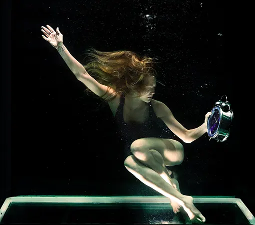 Woman underwater holding round grey clock