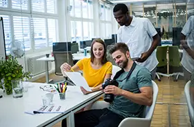 male and female graphic designers discussing a photo in a magazine office