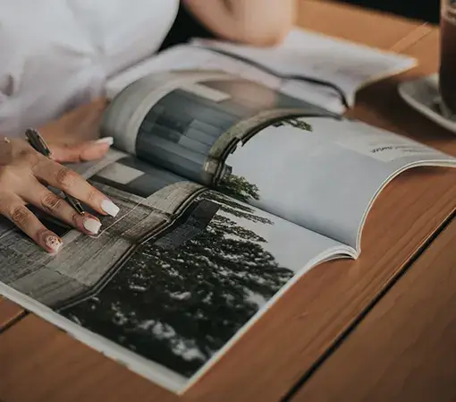 Female editor in white button up shirt proofreading a magazine in her office